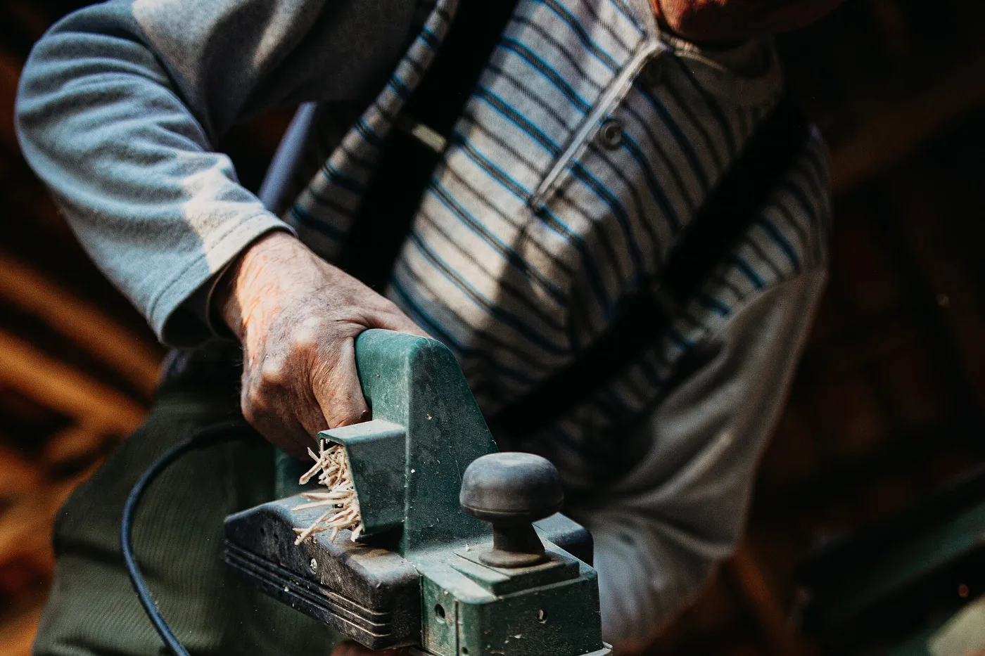 Artisan rabotant une pièce de bois au rabot électrique